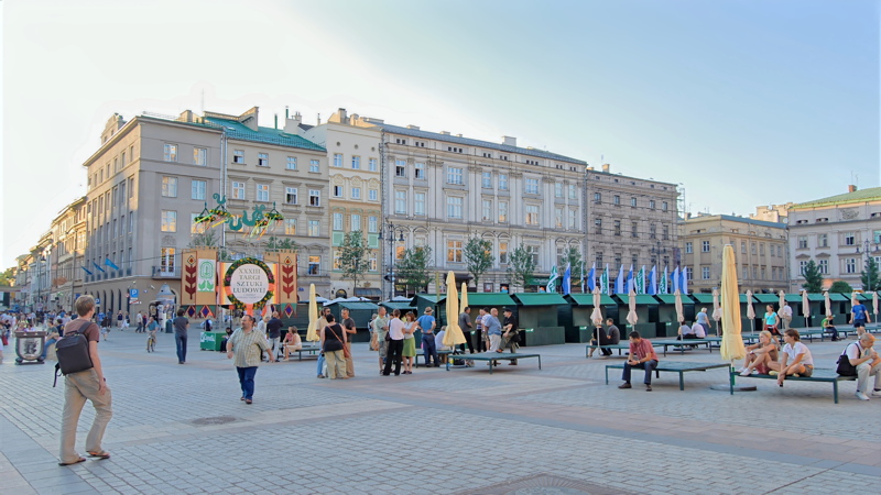 29 - The Main Market Square in Kraków, Poland, featuring historic architecture, open public paving, and temporary market booths set up for an outdoor cultural or folk art event
